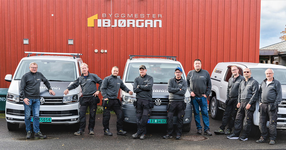 Hele laget til Byggmester Bjørgan samlet — ni fagfolk foran bedriftens kjøretøy.